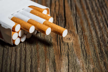 Open pack of cigarettes on old wooden tableの写真素材