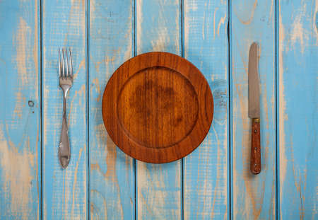 Round wooden plate with knife and forkの写真素材