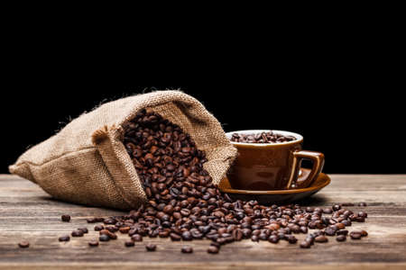 Cup full of coffee beans with sack の写真素材