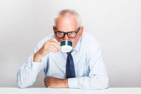 Portrait of an elder businessman drinking coffee overの写真素材