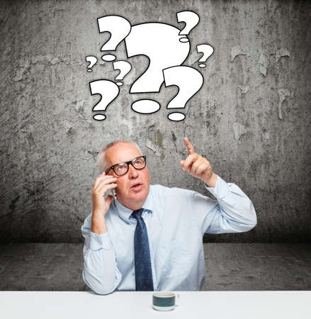Businessman having questions and concrete wall