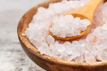 Himalayan pink salt in wooden bowl with kitchen spoonの写真素材