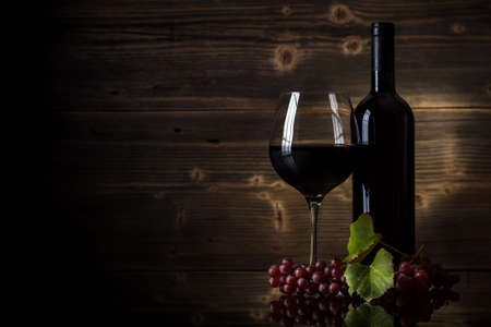 Glass of red wine and bottle with grapeの写真素材