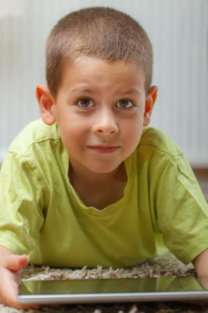 Boy lying on the floor and playing with tablet