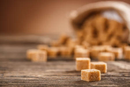 Brown lump sugar on rustic wooden boardの写真素材