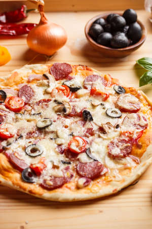 Fresh homemade salami pizza on wooden chopping boardの写真素材