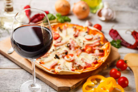 Glass of red wine with pizza on cutting boardの写真素材