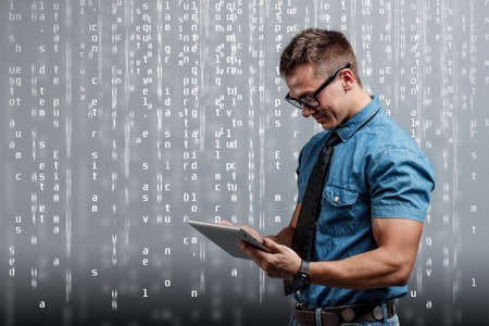 Serious young male executive using digital tablet against gray background の写真素材