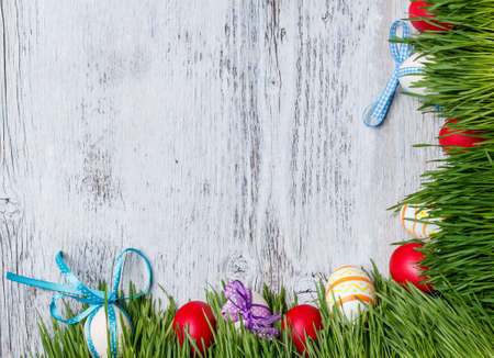 Easter eggs and wooden eggs with ribbon hidden in the grass