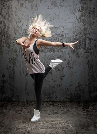 Young beautiful dancer posing on a grunge concrete wall background の写真素材