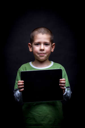 Boy showing tablet computer on black backgroundの写真素材