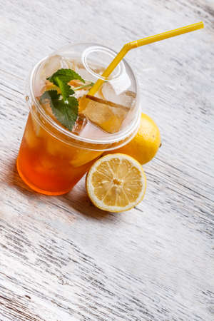 Iced tea in plastic cup with lemon and mintの写真素材