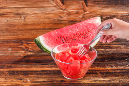 Watermelon cubes in glass bowl served on rustic wooden tableの写真素材
