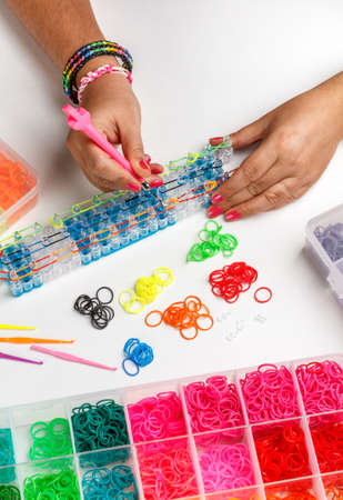 Young woman making a rubber loom bracelet with a hookの写真素材