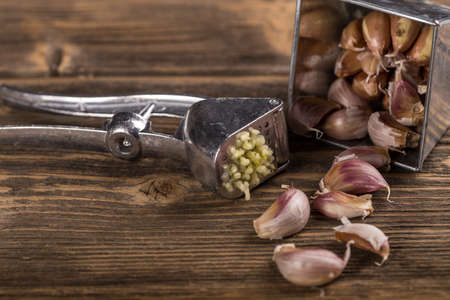 Garlic and garlic press on rustic wooden boardの写真素材