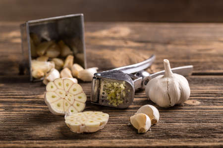 Garlic and garlic press on rustic wooden boardの写真素材