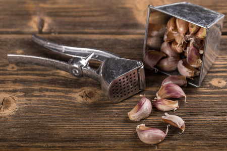 Garlic and garlic press on rustic wooden backgroundの写真素材