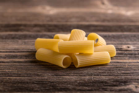 Pile of raw rigatoni on rustic wooden background