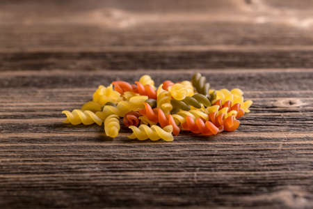 Heap of raw colored pasta fusilli on rustic wooden backgroundの写真素材