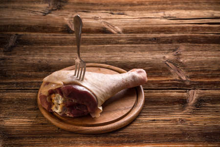 Raw turkey drumstick on a wooden boardの写真素材