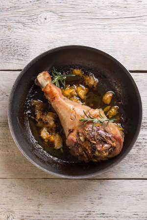 Roasted turkey drumstick in kitchen pan on wooden boardの写真素材