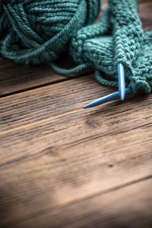 Knitting needles and yarn on wooden background
