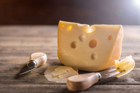 Cheese with fork and knife on rustic wooden backgroundの写真素材