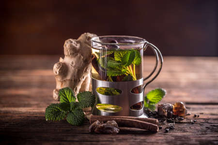 Herbal tea in a glass cup and fresh mint leaves on a wooden boardの写真素材