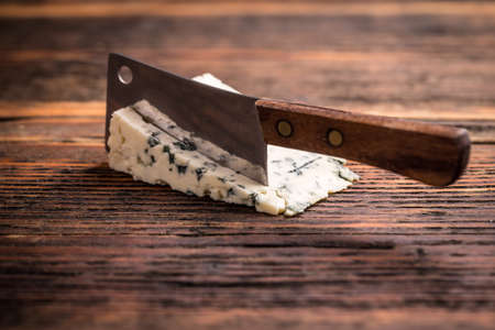 Triangular piece of gorgonzola cheese with knifeの写真素材