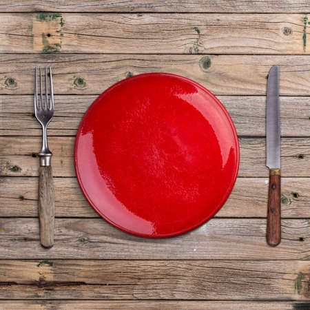 Empty red plate on vintage wooden surfaceの写真素材