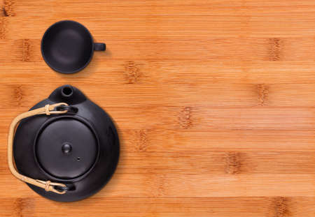 Little black tea cup and a kettle on wooden backgroundの写真素材