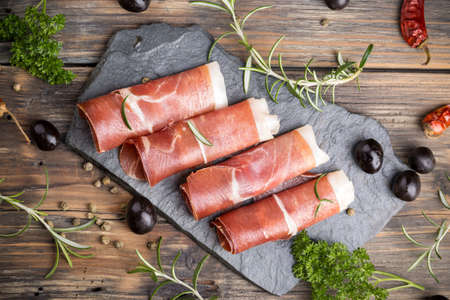 Thin slices of prosciutto with olives and herbsの写真素材