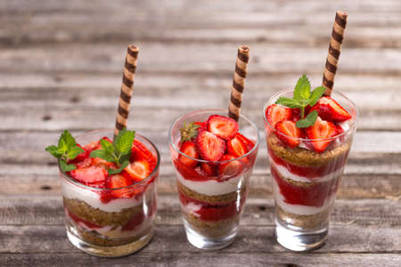 Healthy layered dessert with yogurt cream, muesli and fresh strawberry sauceの写真素材
