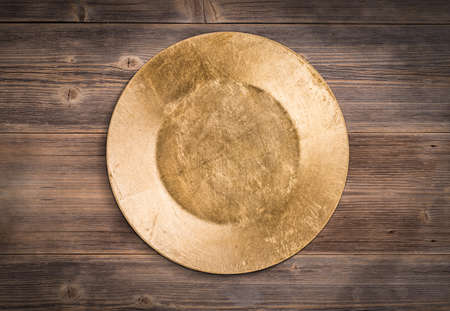 Empty gold plate on wooden backgroundの写真素材