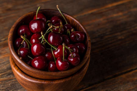 Sour cherry in bowl on wooden backgroundの写真素材