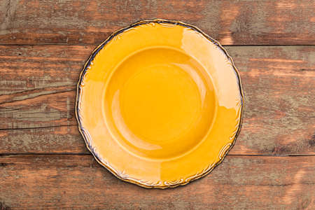 Empty yellow plate on wooden surfaceの写真素材