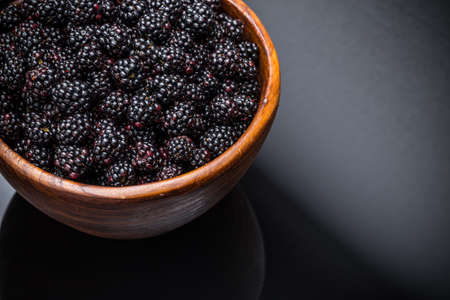 Blackberries in a bowl on black backgroundの写真素材