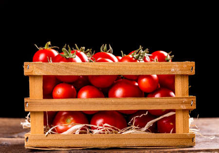 Fresh tomatoes on the vine in a wooden crateの写真素材