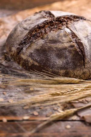 A rustic loaf of sourdough bread on wooden background