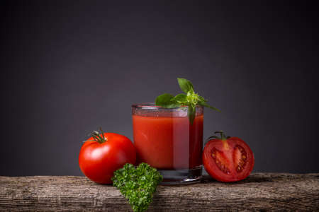 Glass of tomato juice with vegetables on wooden boardの写真素材