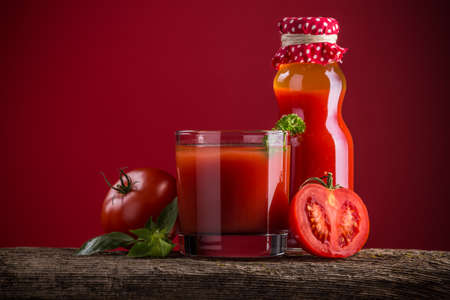 Tomato juice and fresh tomatoes on wooden tableの写真素材