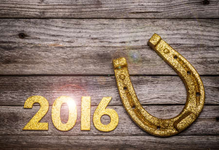Golden horseshoe with golden 2016 number on wooden table backgroundの写真素材