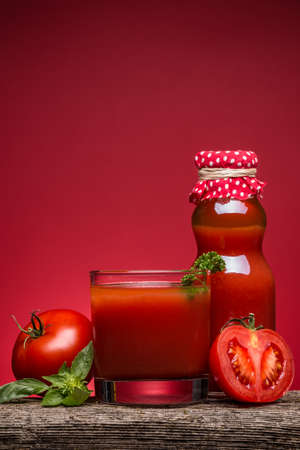 Tomato juice in a glass on a rustic wooden tableの写真素材