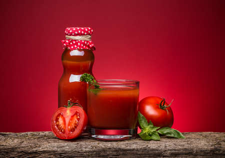 Full bottle and glass of tomato juice with vegetablesの写真素材
