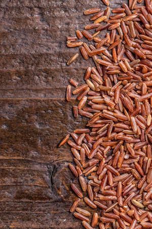 Red rice scattered on weathered wooden backgroundの写真素材
