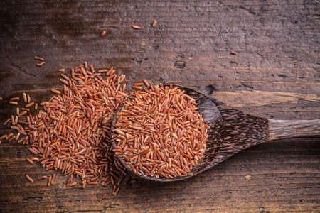 Red rice in wooden spoon on wooden backgroundの写真素材