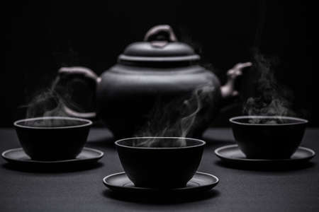 Little black tea cups and a kettle on black backgroundの写真素材
