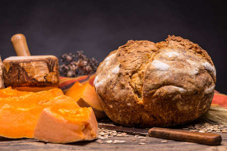 A loaf of bread with pumpkin on wooden backgroundの写真素材