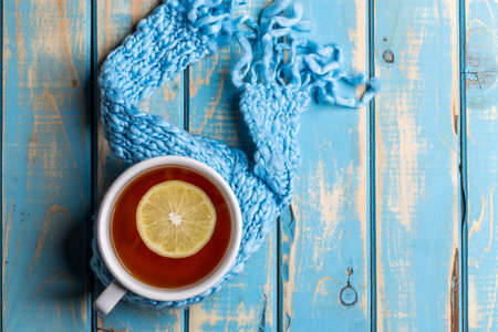 Cup of hot tea with lemon dressed in winter scarfの写真素材