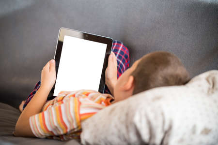 Little boy using a digital tablet in bed
